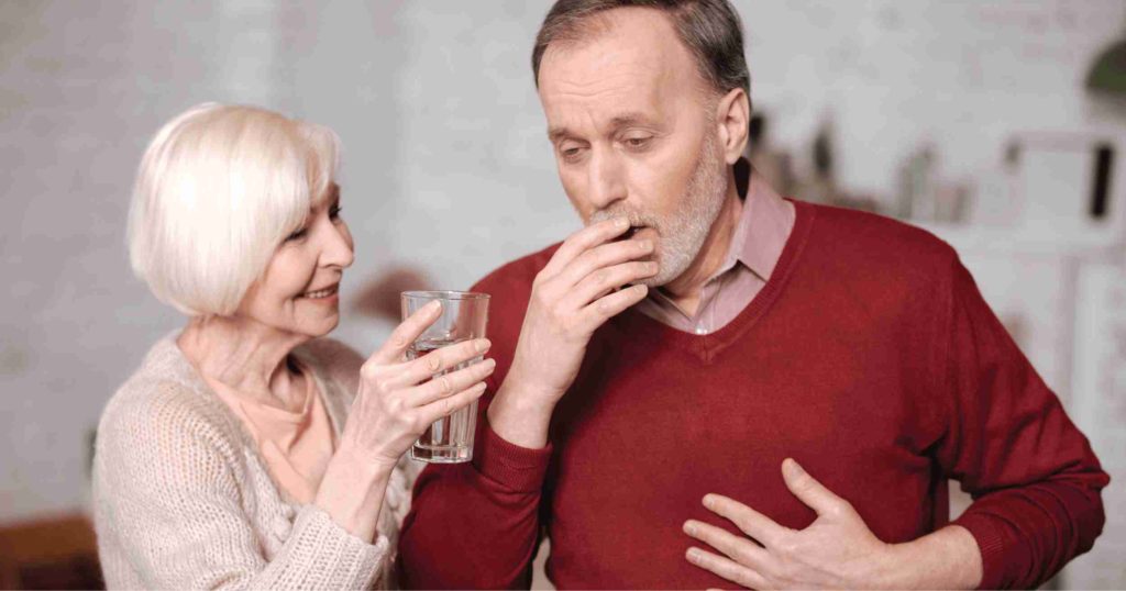 An old man coughing badly and his while trying to give to him some water